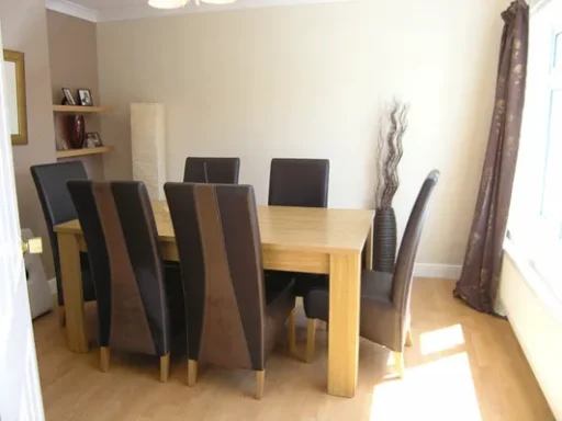 A modern dining room with a large wooden table and eight brown upholstered chairs.